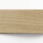 Prostokątna próbka drewna w jasnym, naturalnym kolorze zabezpieczona lakierem bezbarwnym, prezentująca wyraźny i regularny układ słojów na białym tle.