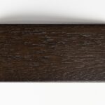 Prostokątna próbka drewna w głębokim, ciemnobrązowym kolorze orzecha z wyraźnie zaznaczoną strukturą naturalnych słojów i mikrowgłębień, zaprezentowana w poziomie na białym tle.
